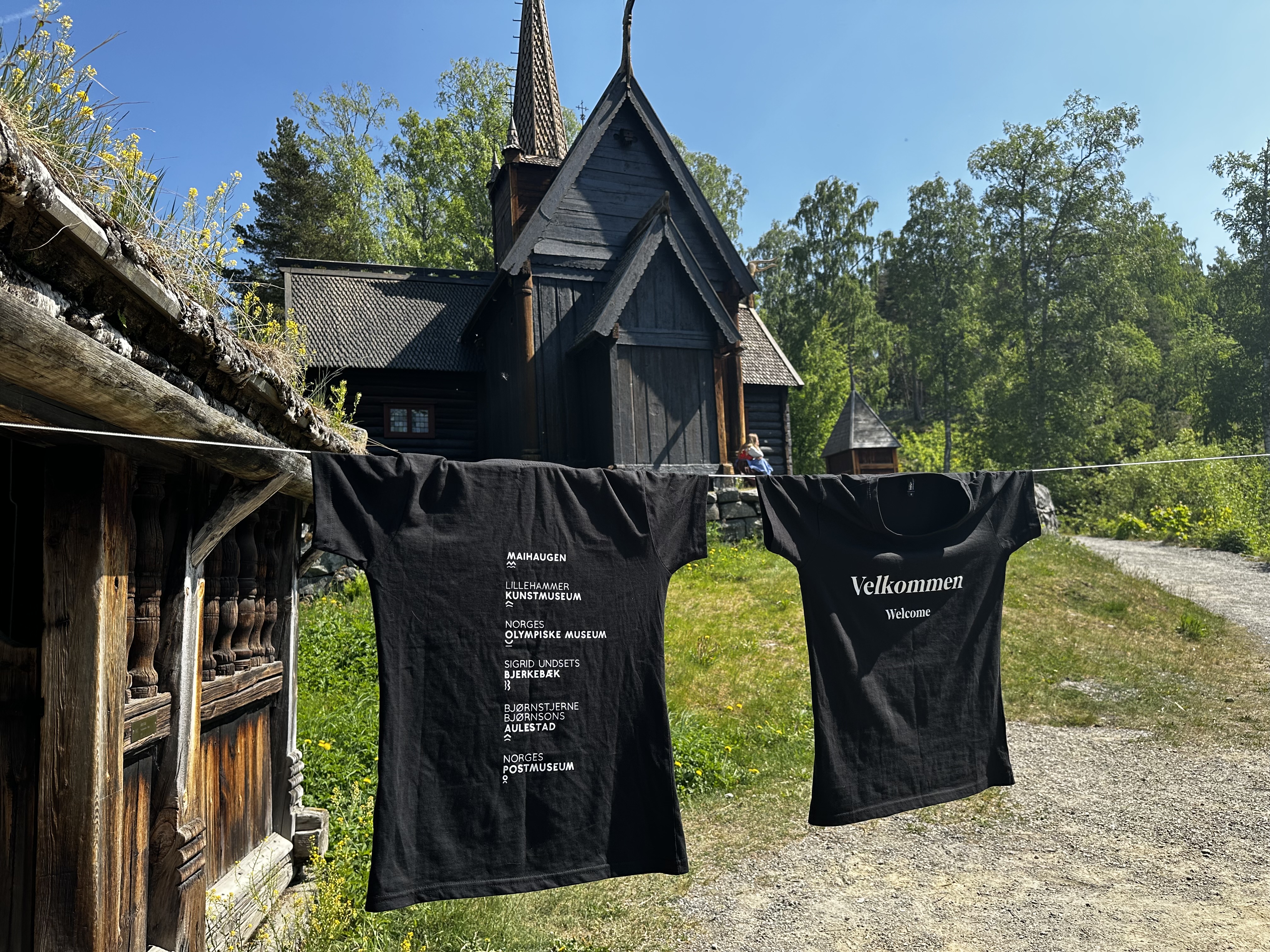 T-skjorter med trykk hengende til tørk foran en stavkirke
