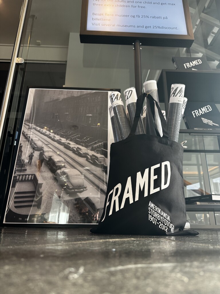 Handlenett med trykket Framed foran plakater og en skjerm