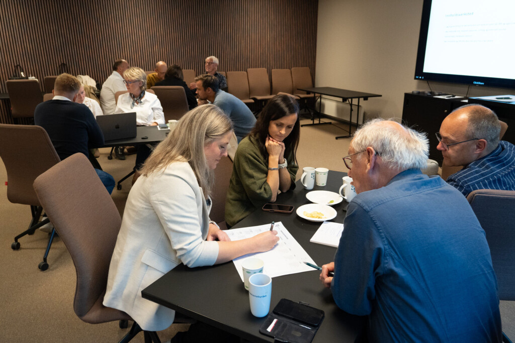 Deltakere jobber sammen rundt et bord under en workshop